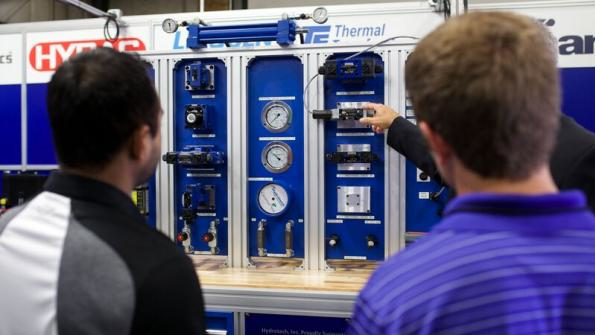 People listen to a demonstration on one of four brandnew hydraulic training stands The training assemblies valued at 30000 per unit will be used by students in Cincinnati Statersquos ElectroMechanical Engineering Technologies program to build modern manufacturing skills