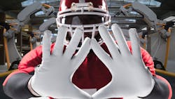 Football player holding out hands over background photo of robotic arms Football player holding out hands over background photo of robotic arms