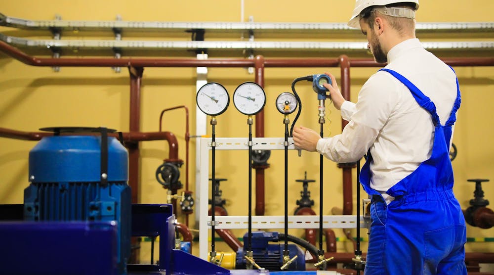 Engineer adjusts pressure sensors on industrial refinery plant