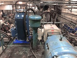 Installation of newer hydraulic pumps allowed for a more compact, space saving design on GEI&apos;s extrusion press. The right side of the photo shows the legacy, horizontally installed pump and power unit, the left side shows the vertically installed new power unit; the pump itself is installed in the reservoir.