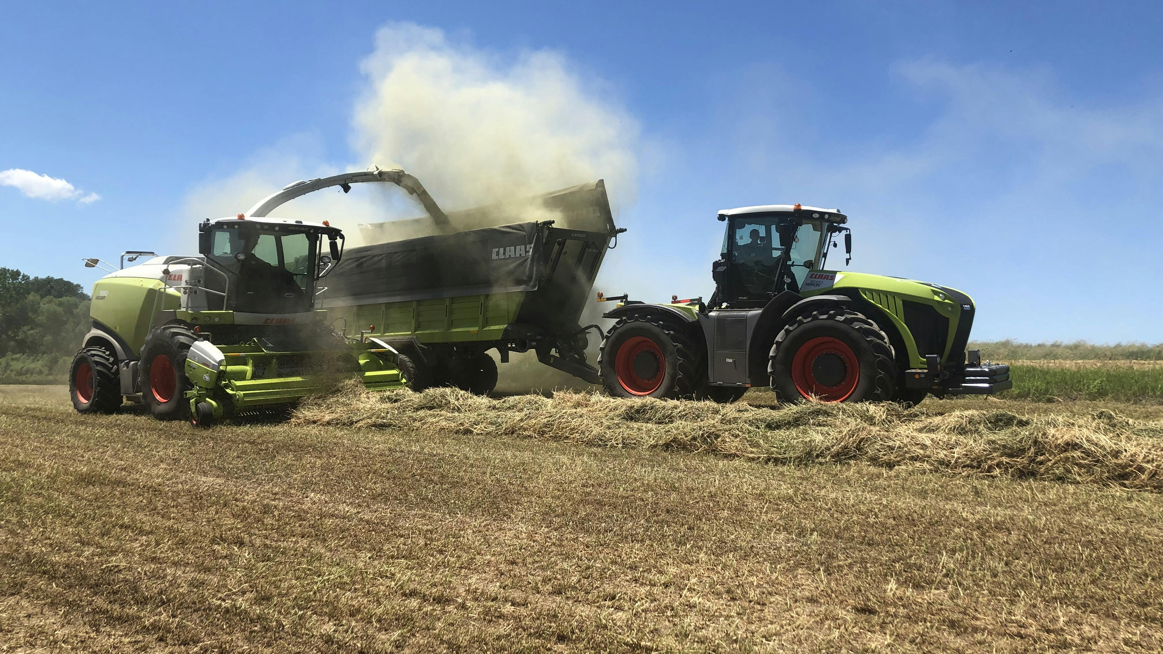 A combine and tractor working in a farm field