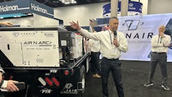 A company executive gesturing toward a new product introduction A company executive gesturing toward a new product introduction