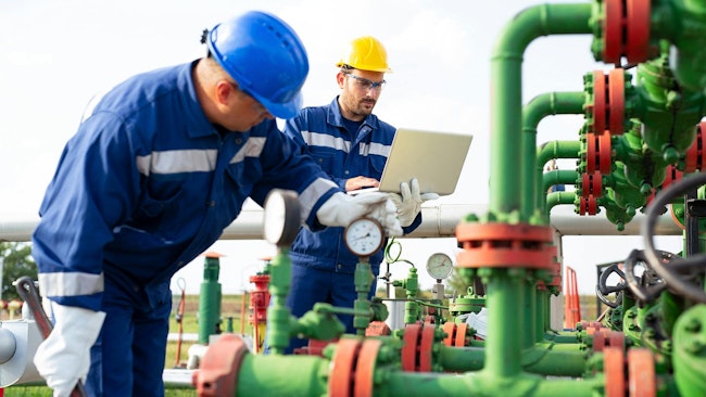 An image of maintenance workers examining some piping and other components
