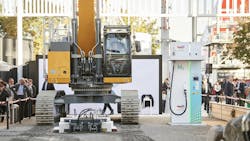 An electric excavator and charging station on display at a trade show An electric excavator and charging station on display at a trade show