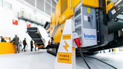 An electric construction machine plugged into a charging station An electric construction machine plugged into a charging station
