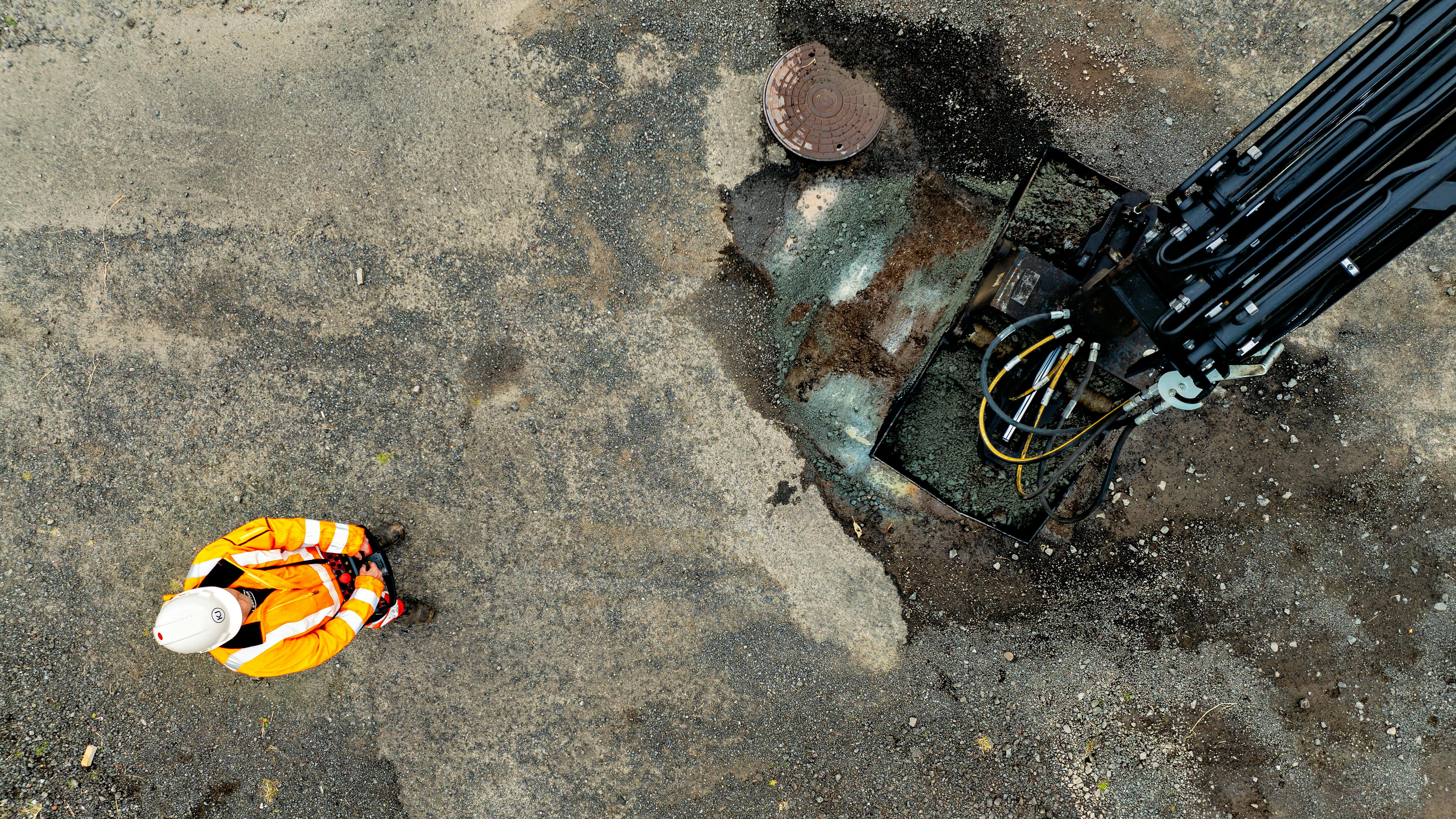 A person standing near a machine which is being remotely controlled