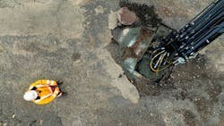 A person standing near a machine which is being remotely controlled A person standing near a machine which is being remotely controlled