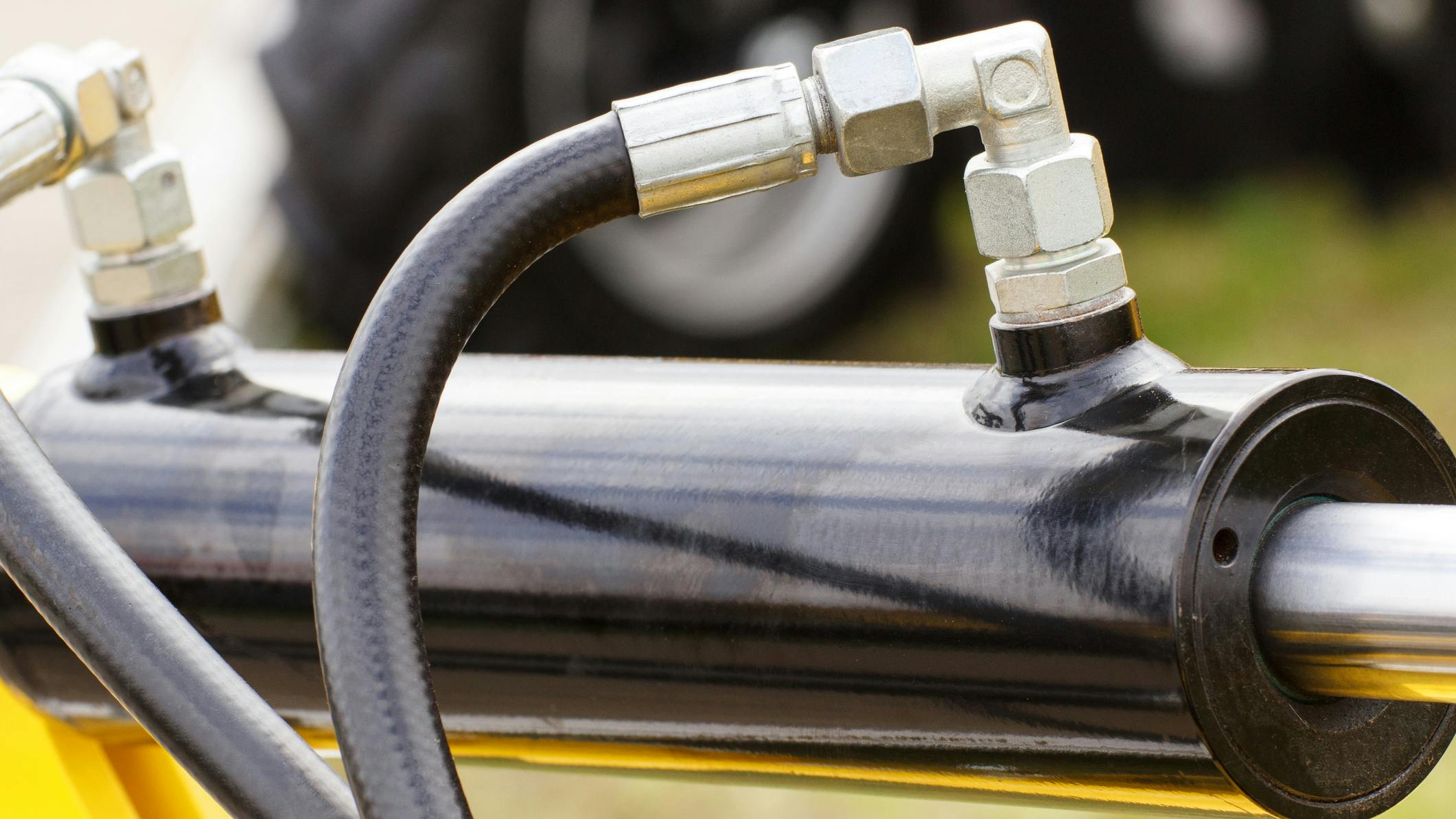 A close up view of a hydraulic cylinder and hoses connected to it
