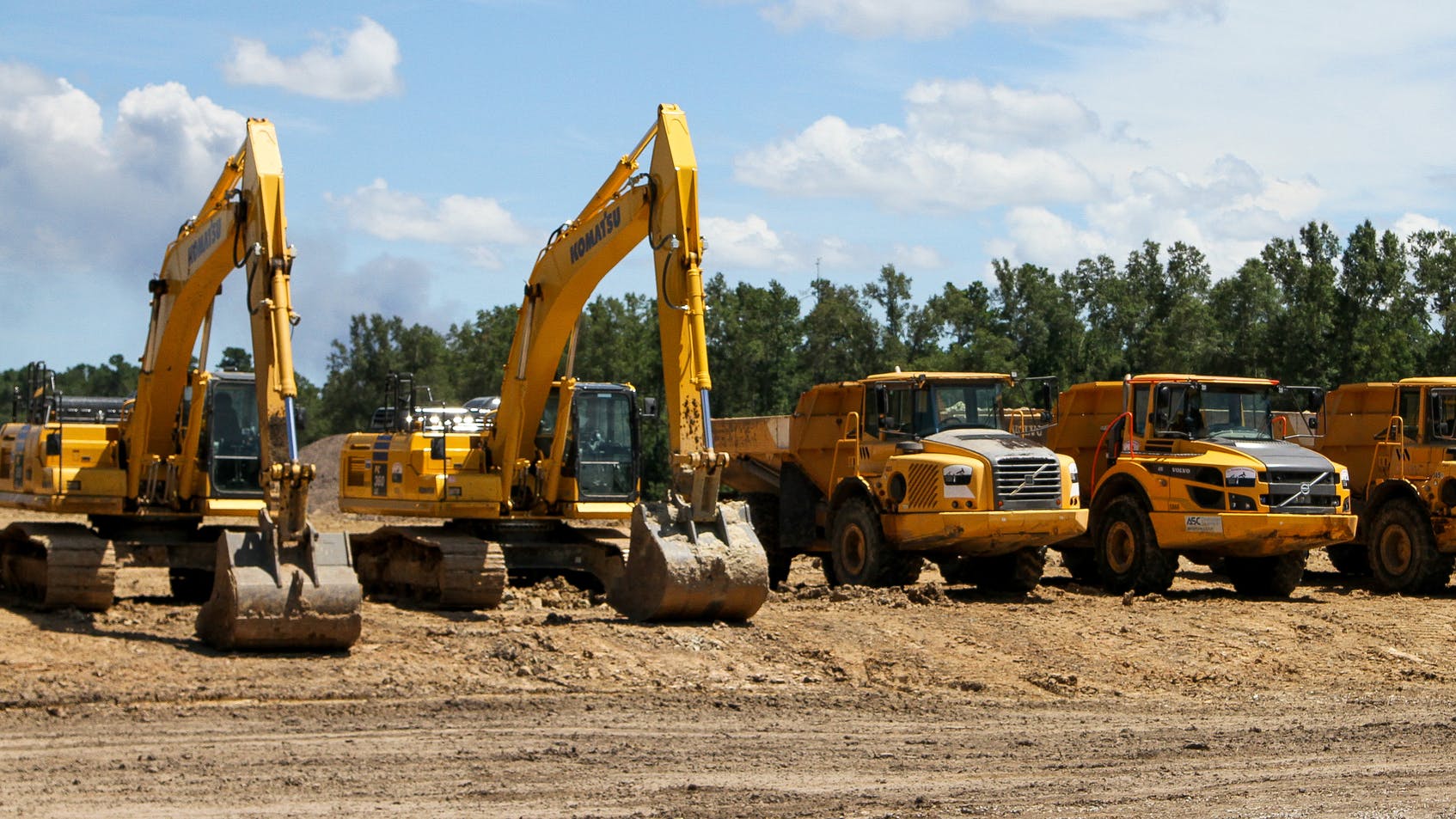 Excavators and articulated haulers lined up on a construction job site