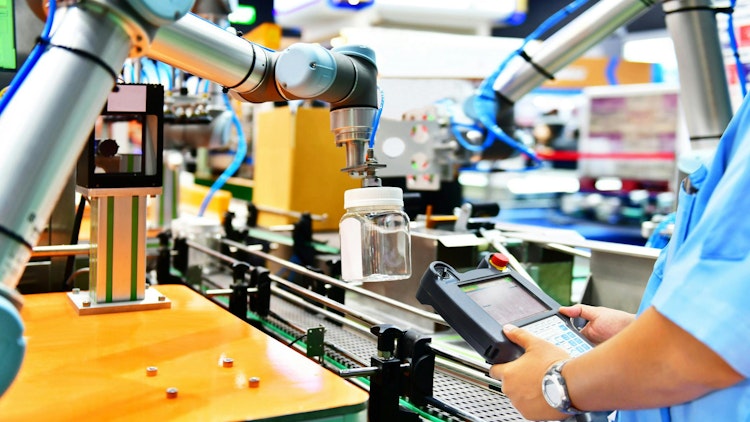 A cobot picking up a glass bottle with a human worker observing