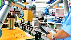 A cobot picking up a glass bottle with a human worker observing A cobot picking up a glass bottle with a human worker observing