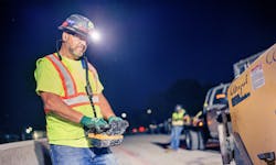 A construction worker remotely controlling a machine on a job site A construction worker remotely controlling a machine on a job site