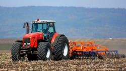 A tractor pulling an implement in a farm field A tractor pulling an implement in a farm field