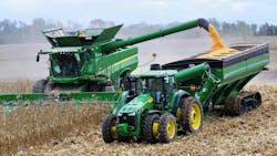 A combine and tractor working side by side in a farm field A combine and tractor working side by side in a farm field