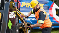 A technician performing hydraulic hose services on a piece of construction equipment