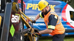 A technician performing hydraulic hose services on a piece of construction equipment A technician performing hydraulic hose services on a piece of construction equipment