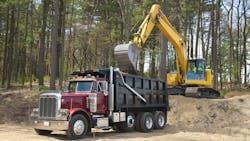 Excavator putting material into the bed of a dump truck on a construction site Excavator putting material into the bed of a dump truck on a construction site