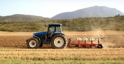 Tractor pulling an implement through a farm field Tractor pulling an implement through a farm field