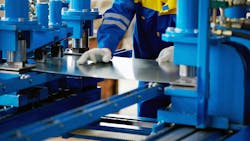 Worker moving sheet metal through a press Worker moving sheet metal through a press