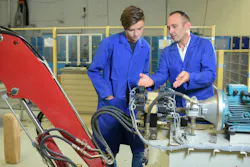 Engineers looking at a hydraulic machine setup Engineers looking at a hydraulic machine setup