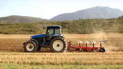 Blue tractor pulling an implement through a farm field Blue tractor pulling an implement through a farm field