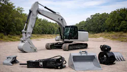 A grey excavator and various types of attachments in the foreground A grey excavator and various types of attachments in the foreground