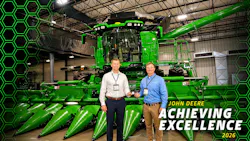 Trelleborg employees holding partner-level supplier award standing in front John Deere combine Trelleborg employees holding partner-level supplier award standing in front John Deere combine