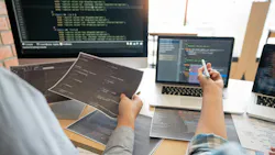 Computer screens with code and two hands point toward it Computer screens with code and two hands point toward it