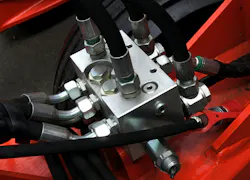 Close up on hydraulic hoses, fittings and a manifold in a machine