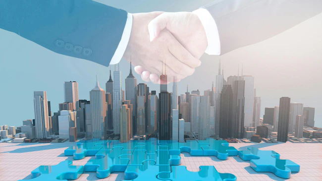 Two hands shaking over puzzle pieces and superimposed over office buildings to provide concept of business mergers and acquisitions