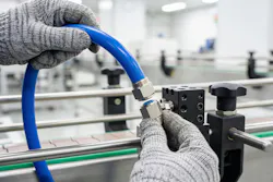 Two gloved hands assembling pneumatic components for a conveyor system