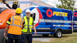 Two men shaking hands in front of a machine and PIRTEK hose service work van