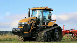 Yellow tractor pulling a red implement in a farm field