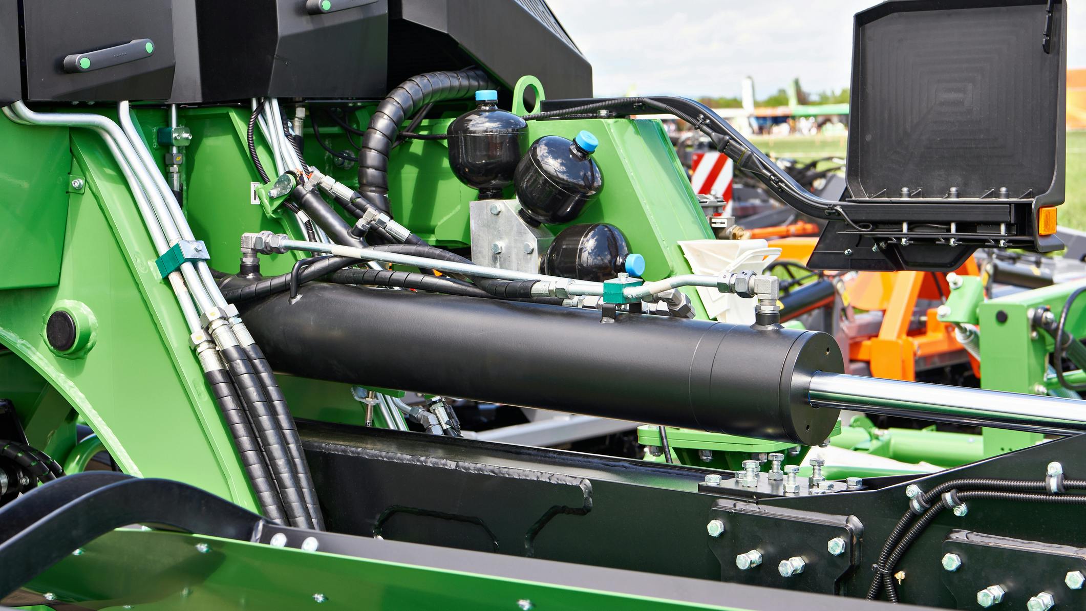 Close up view on hydraulic hoses, cylinders and other components on a green colored machine