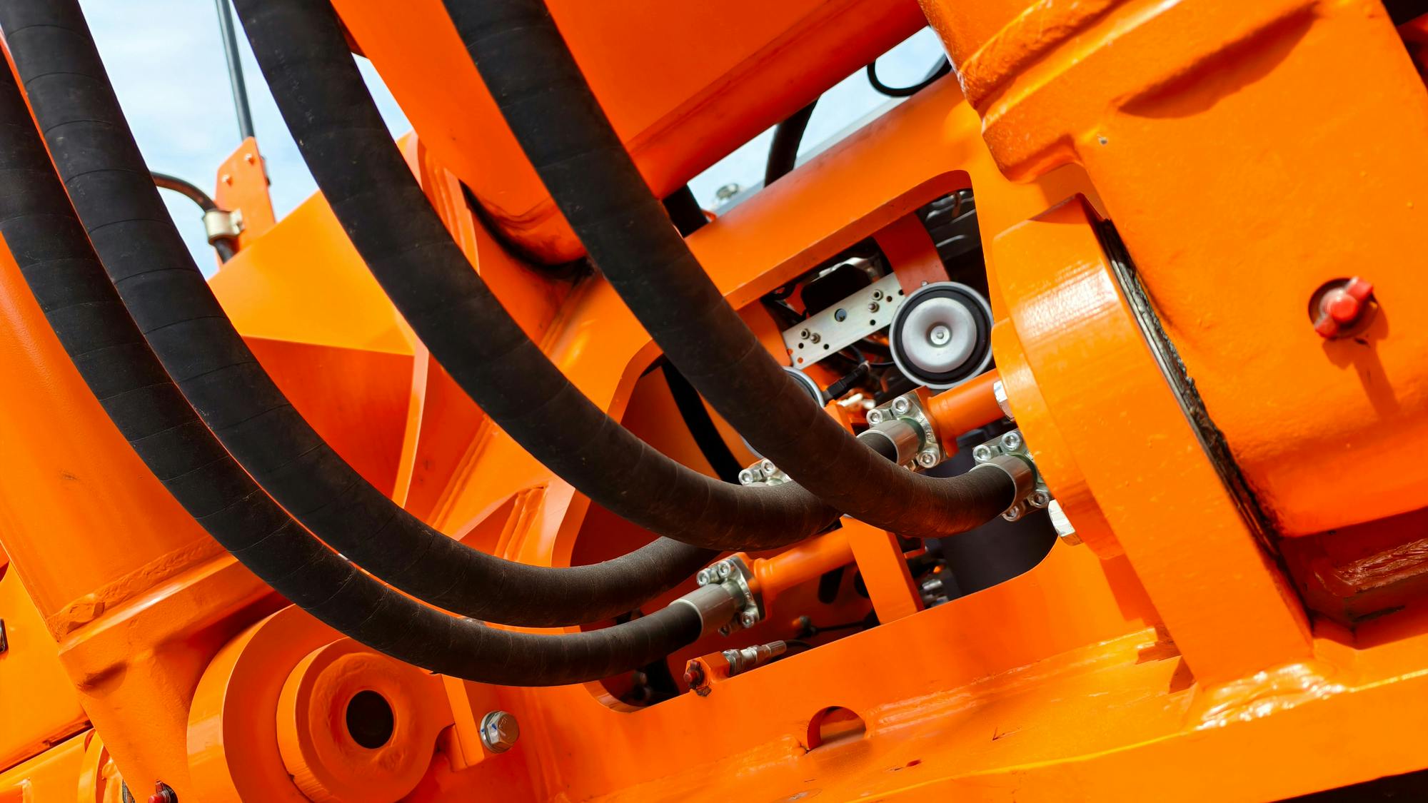 Underside view of hydraulic hoses on an orange colored machine