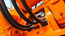 Underside view of hydraulic hoses on an orange colored machine