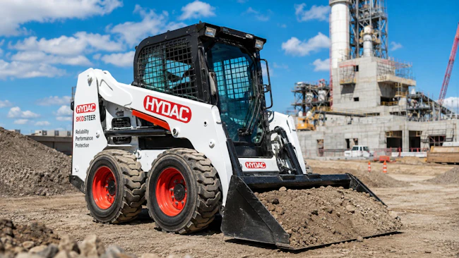 Skid steer with HYDAC logo working on a job site
