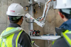Two workers watch the Schindler Elevator Installation Robot Complete its Work
