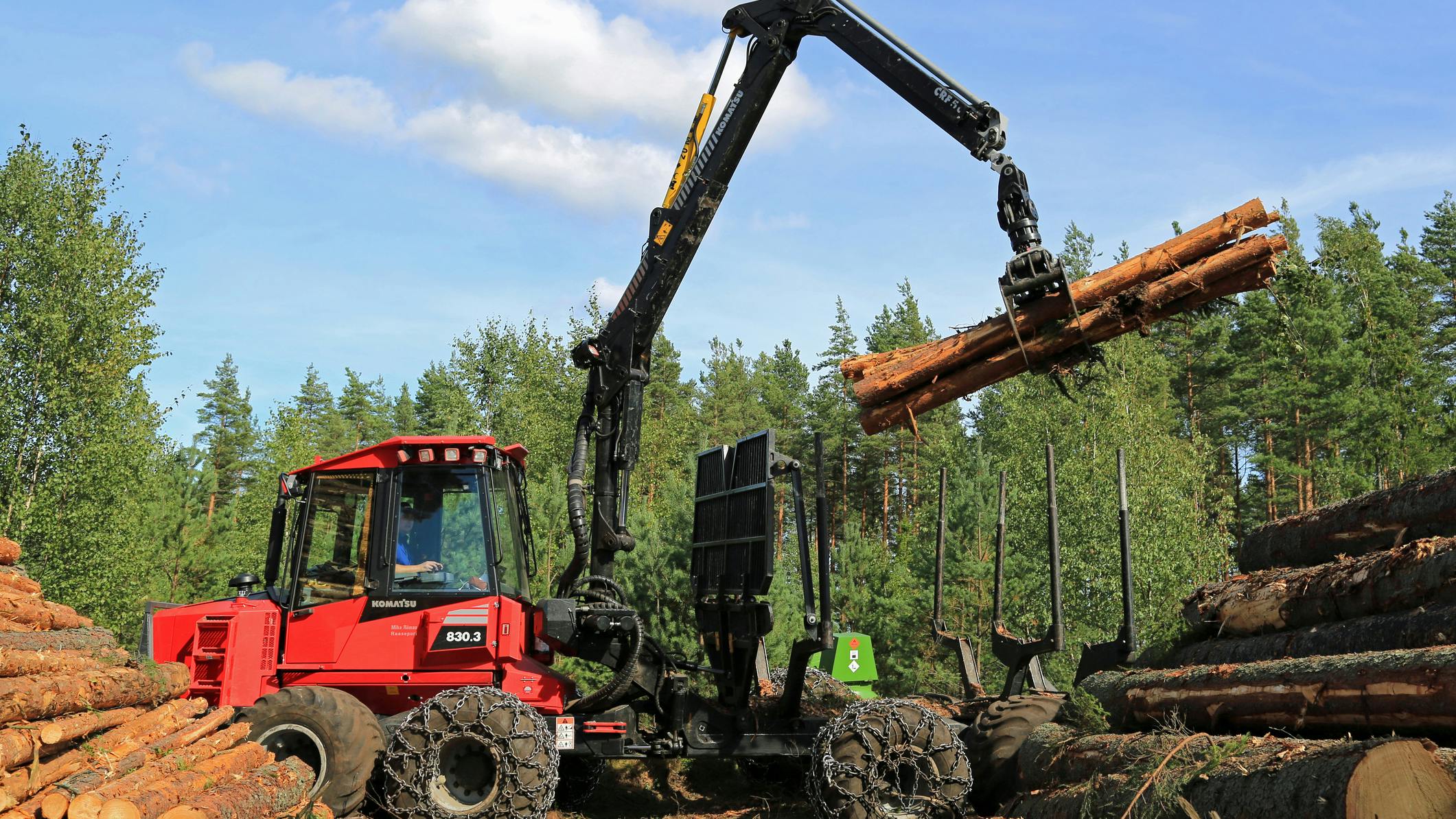 Forestry Machine lifting several logs on a job site